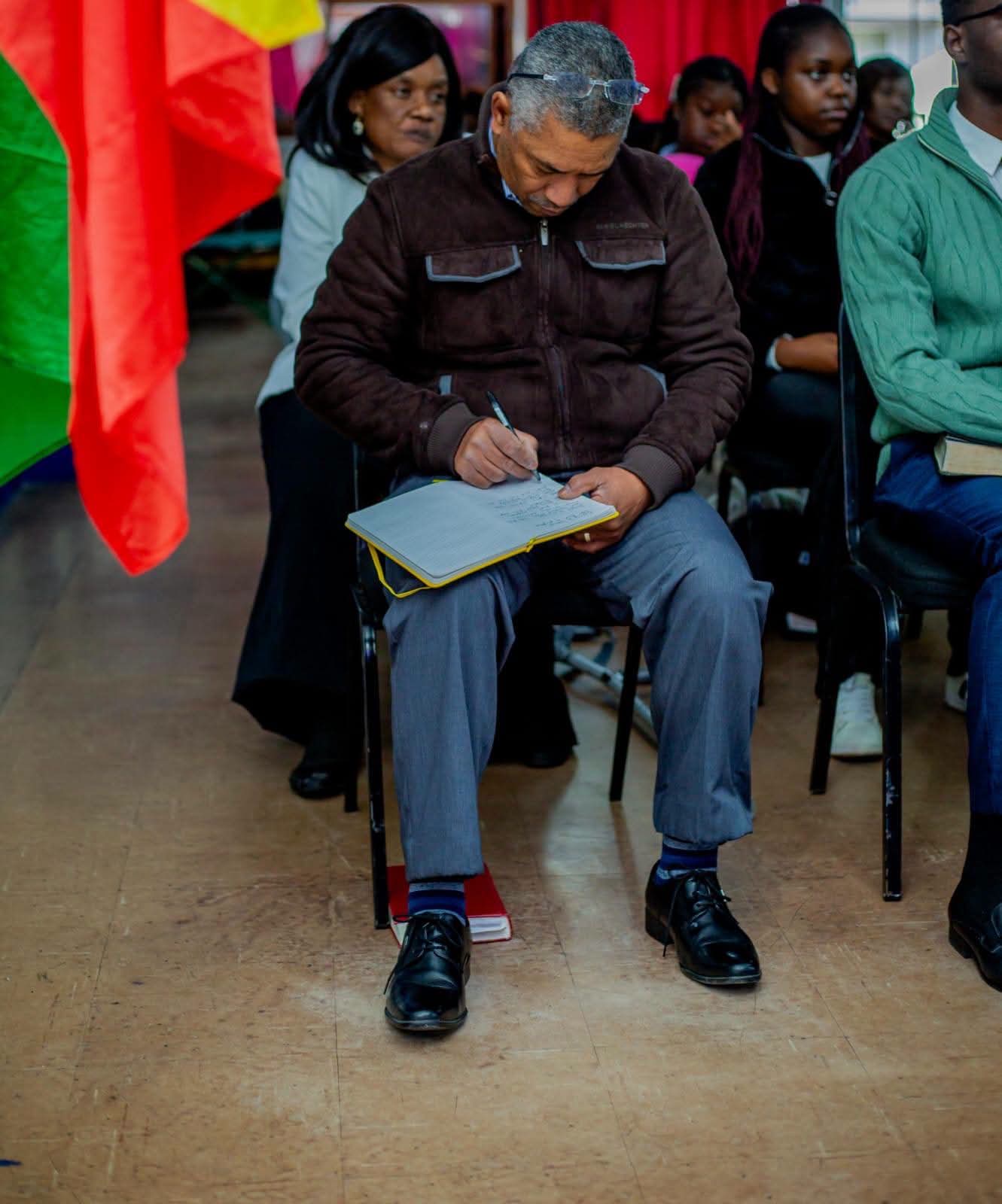 A believer taking notes while the Word is taught during a service