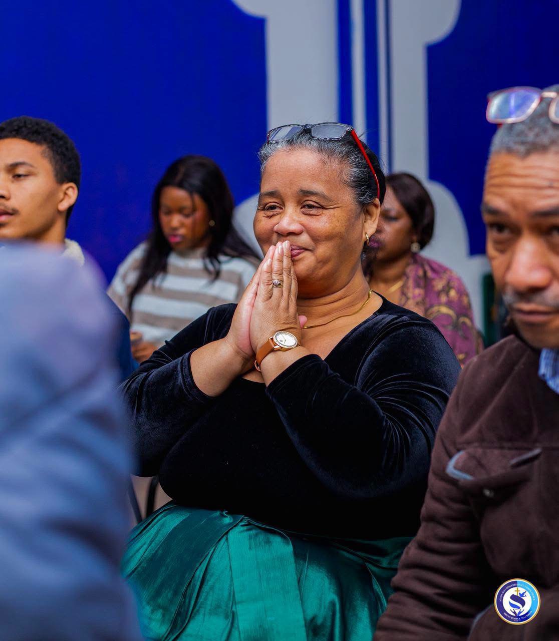 A member of the congregation in prayer with hands clasped during worship